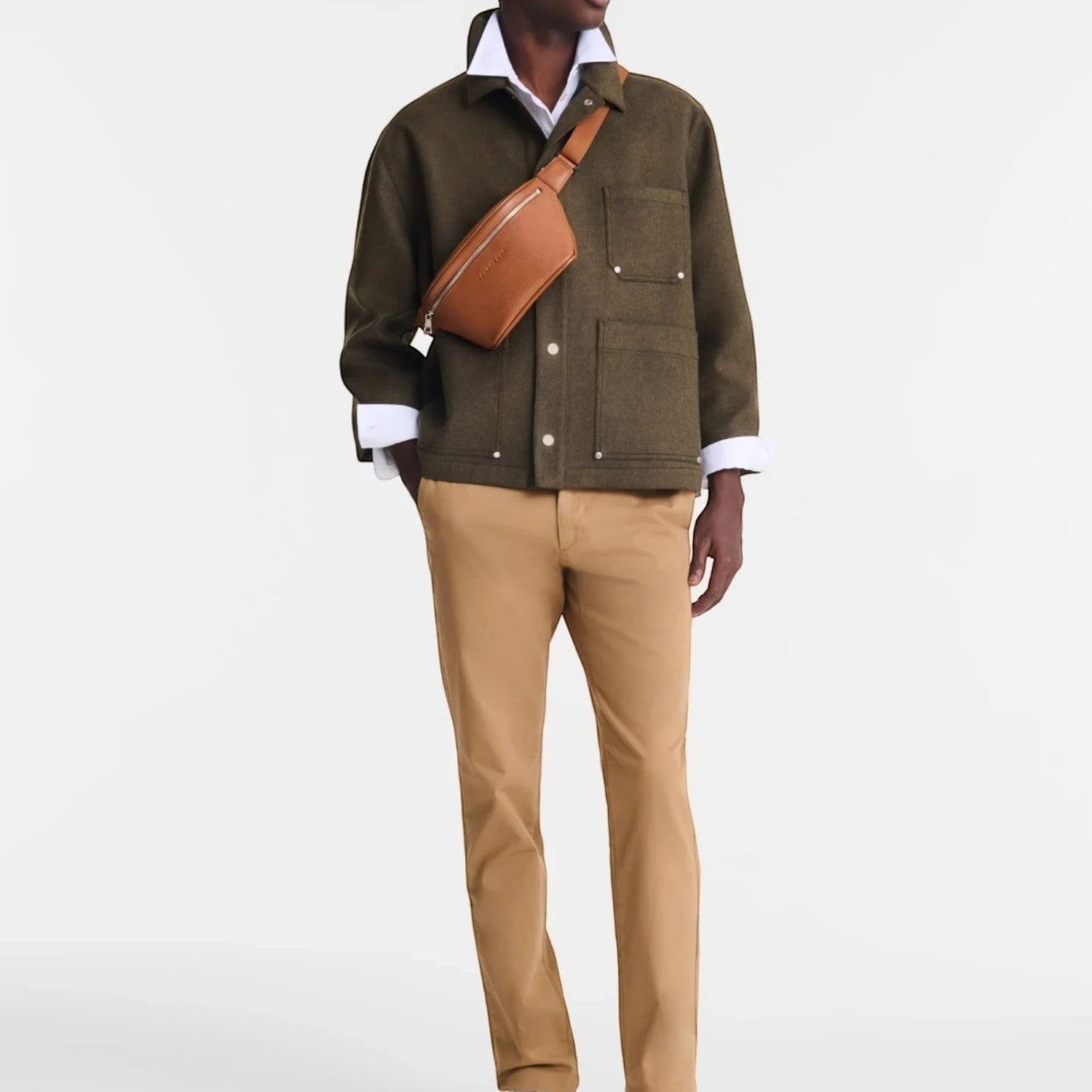 Lieblingstasche Le Foulonné tan leather belt bag worn across the chest by a man in an olive jacket and beige trousers