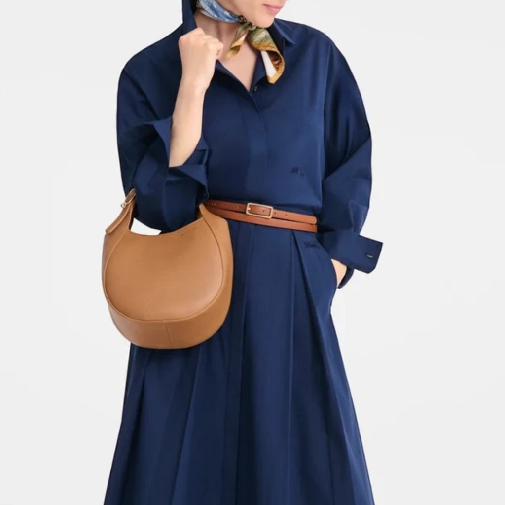 Lieblingstasche Le Foulonné small tan leather hobo bag worn by a woman in a navy blue dress