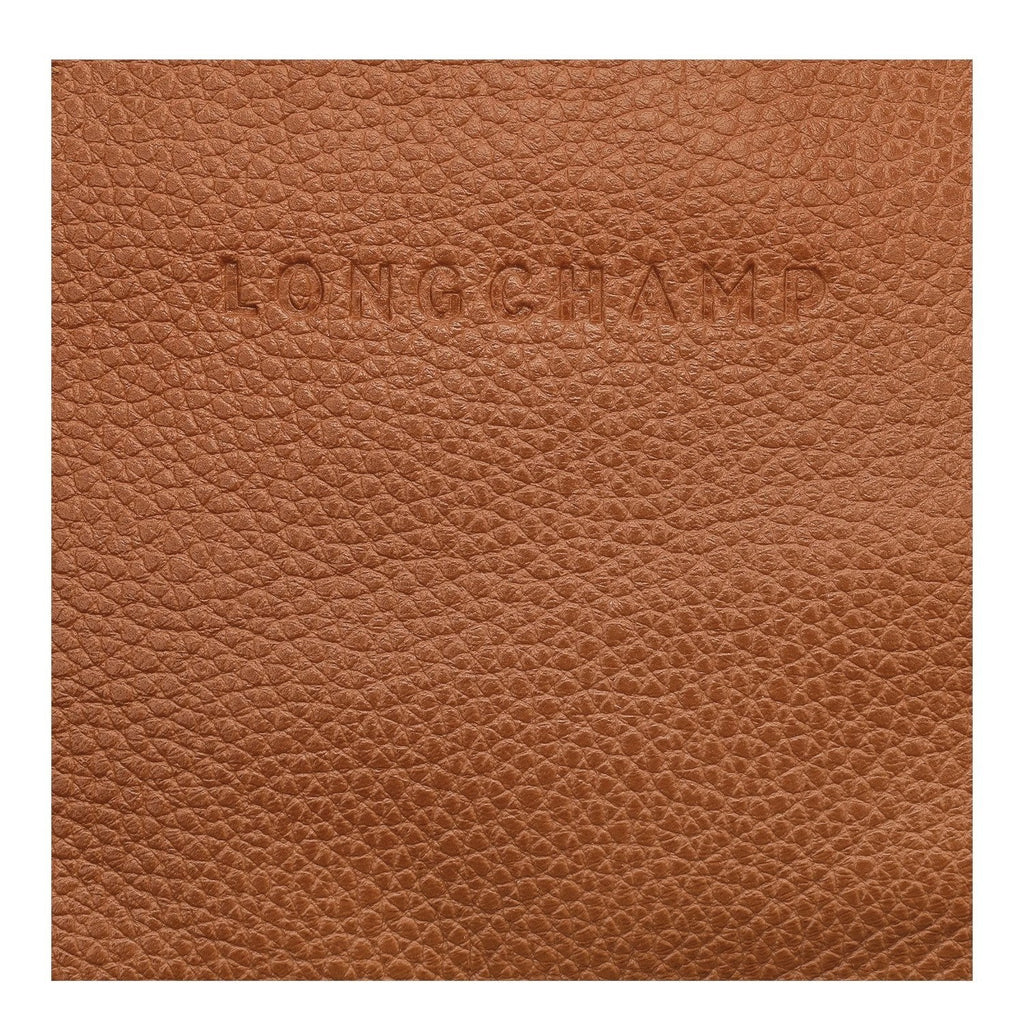 Close-up of tan grained leather texture with embossed Longchamp logo from Lieblingstasche Le Foulonné belt bag