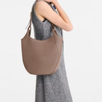 Lieblingstasche Le Foulonné shoulder bag in taupe grained leather worn over the shoulder by a woman in a grey dress