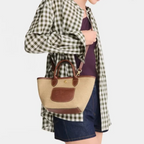Lieblingstasche Le Panier Pliage XS straw-effect crossbody bag with brown leather trim worn by a model