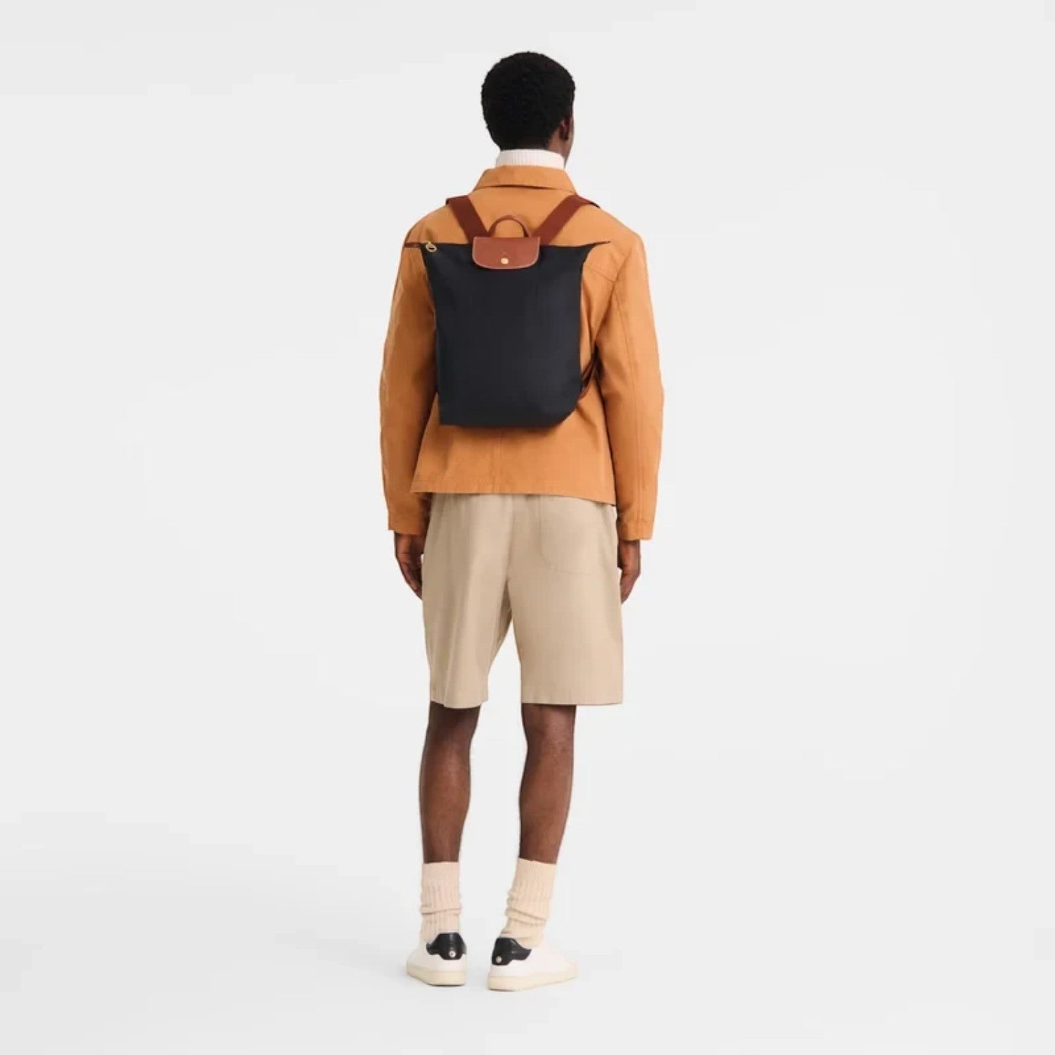 Lieblingstasche Le Pliage black nylon rucksack with brown leather flap and straps worn by a man from behind