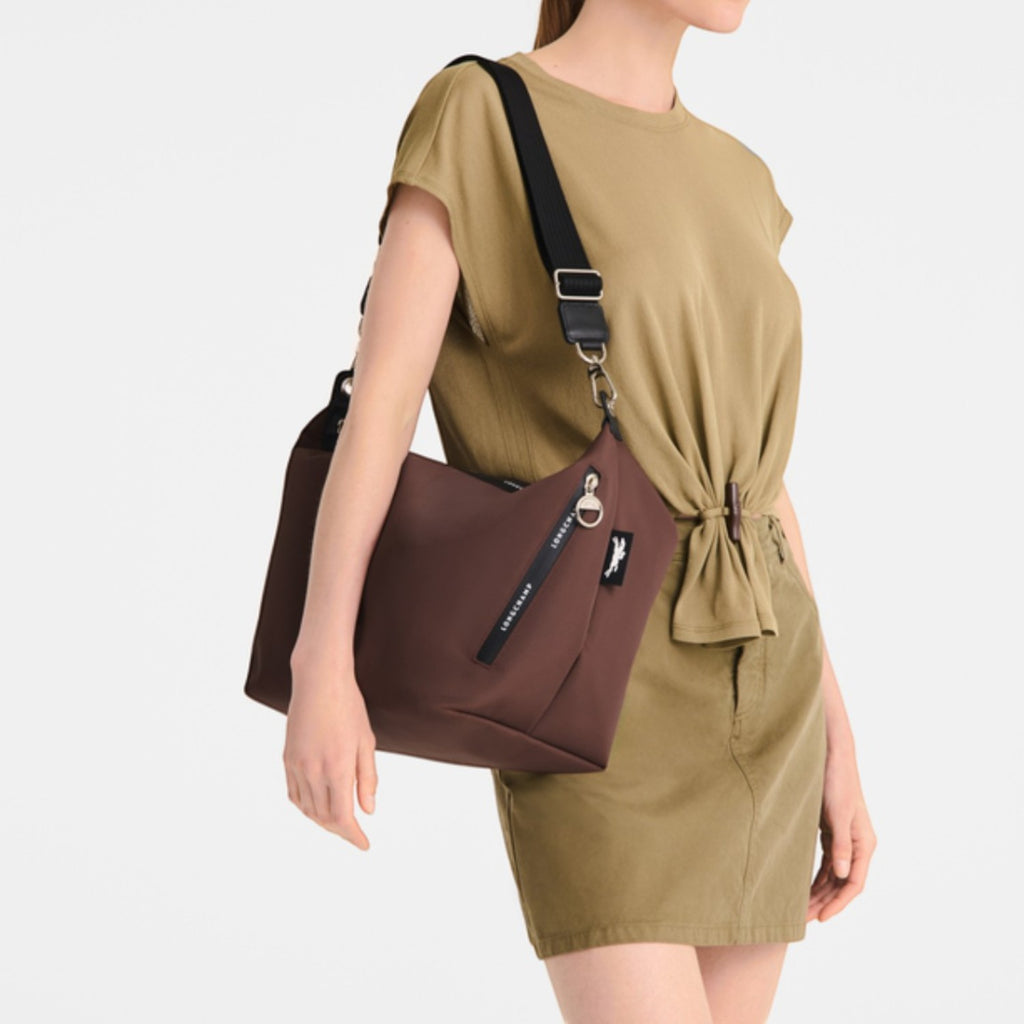 Lieblingstasche Le Pliage Energy medium brown crossbody bag worn by a model in a matching olive outfit.