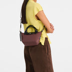 Lieblingstasche Le Pliage Energy XS handbag in brown recycled nylon with black handles and rope detail worn by model
