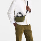 Lieblingstasche Le Pliage Energy XS olive green recycled nylon handbag with black rope detail worn by a male model