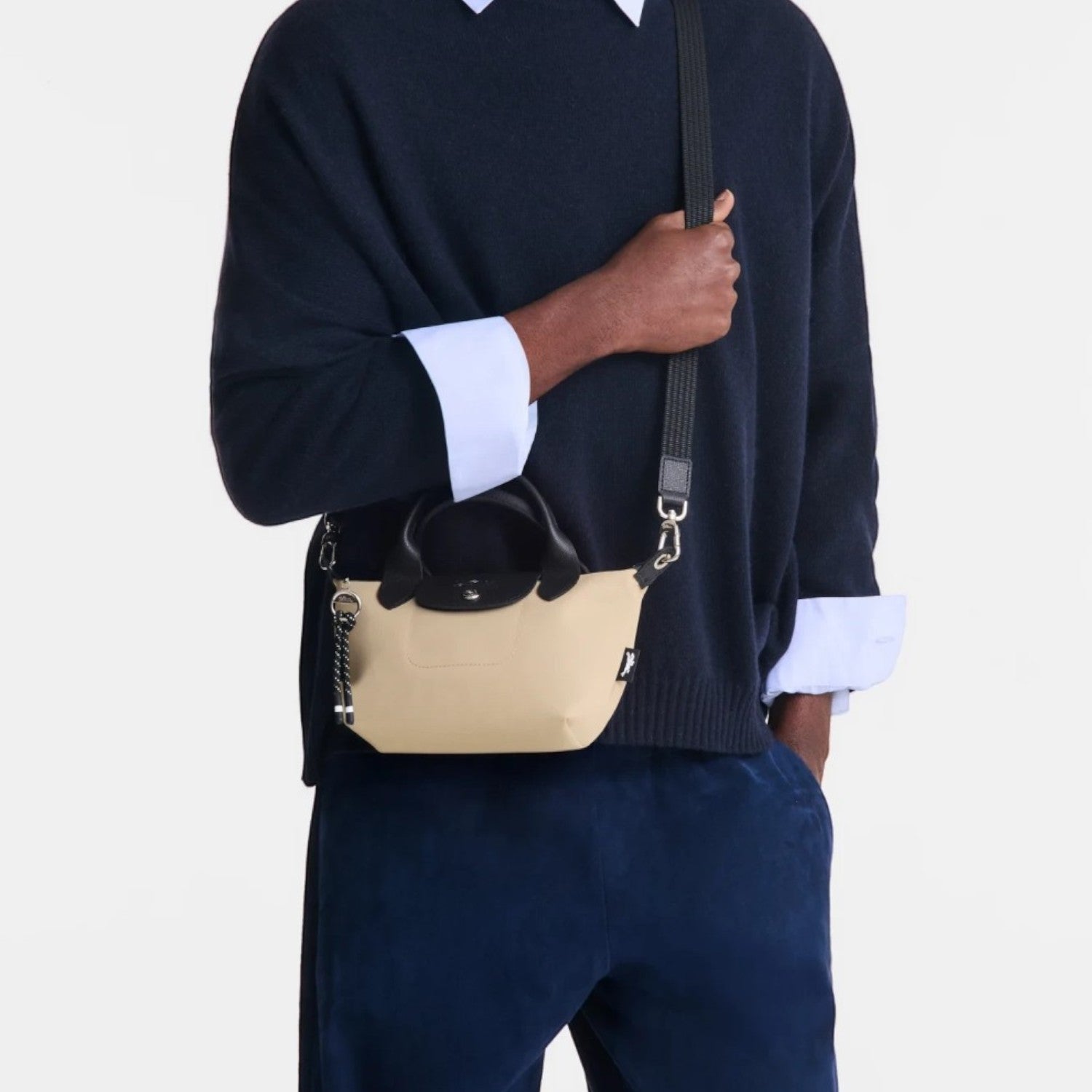 Lieblingstasche Le Pliage Energy XS handbag in beige recycled nylon with black rope detail worn by a male model