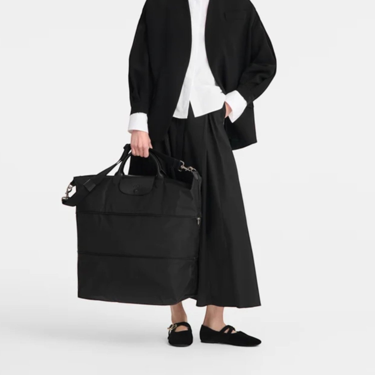 Lieblingstasche Le Pliage One black nylon travel bag with leather trim and handles, worn by a model.