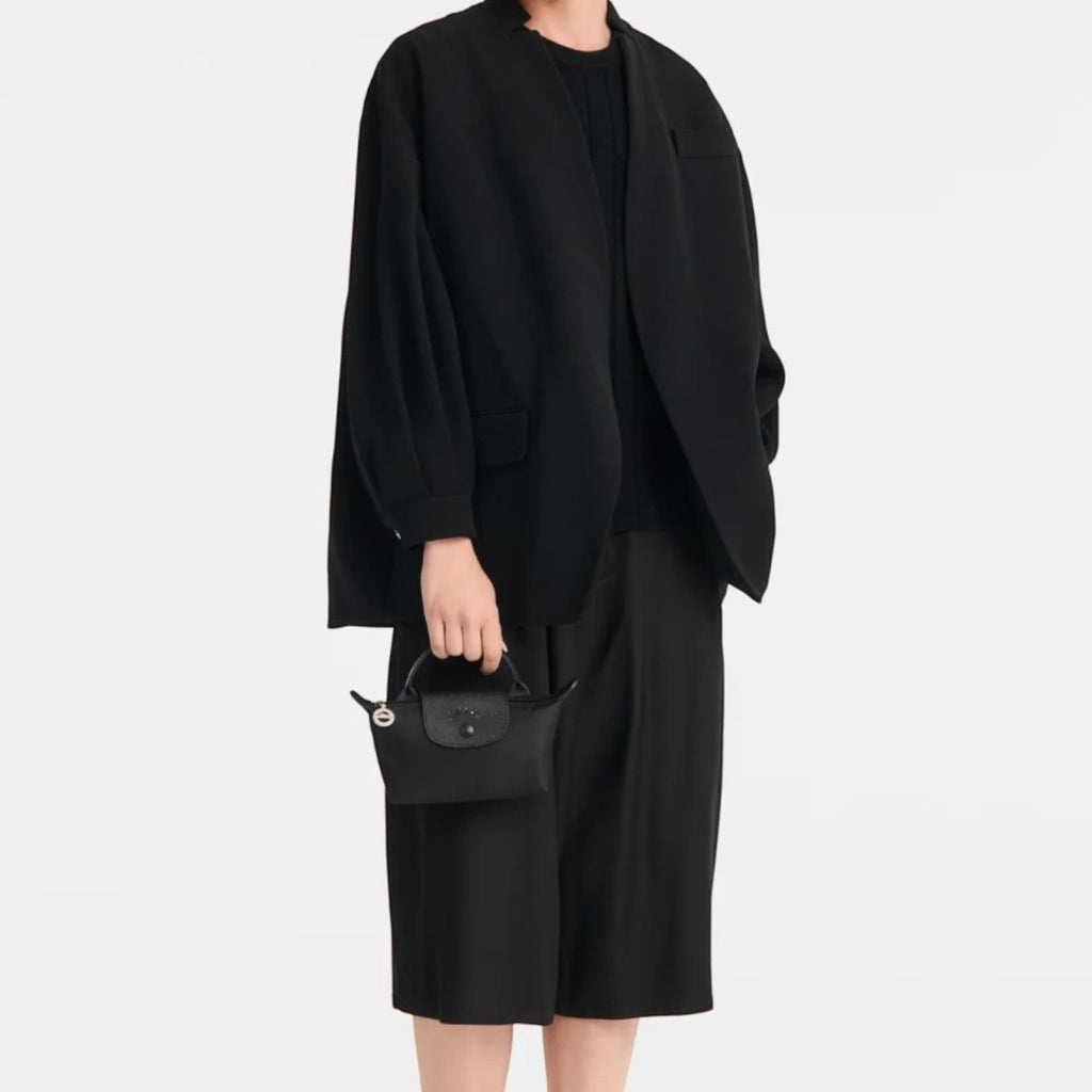 Model wearing all-black outfit holding a compact Lieblingstasche Le Pliage One black pochette handbag