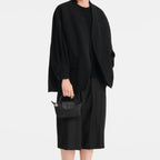 Model wearing all-black outfit holding a compact Lieblingstasche Le Pliage One black pochette handbag
