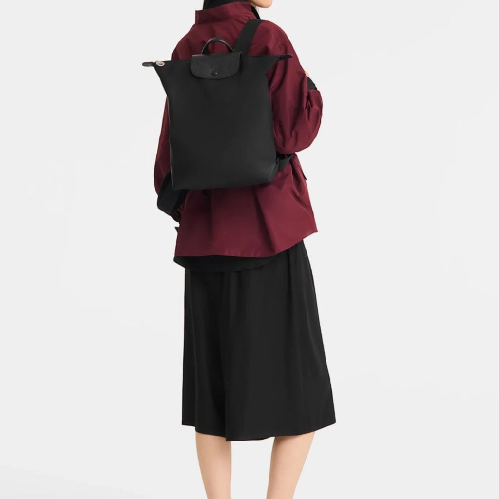 Model wearing a black Lieblingstasche Le Pliage One rucksack with a minimalist design against a white background