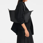 Lieblingstasche Le Pliage One black nylon tote bag with leather handles, worn by a model.