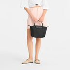 Lieblingstasche Le Pliage One handbag in black nylon with leather trim and handles. Model holds bag.