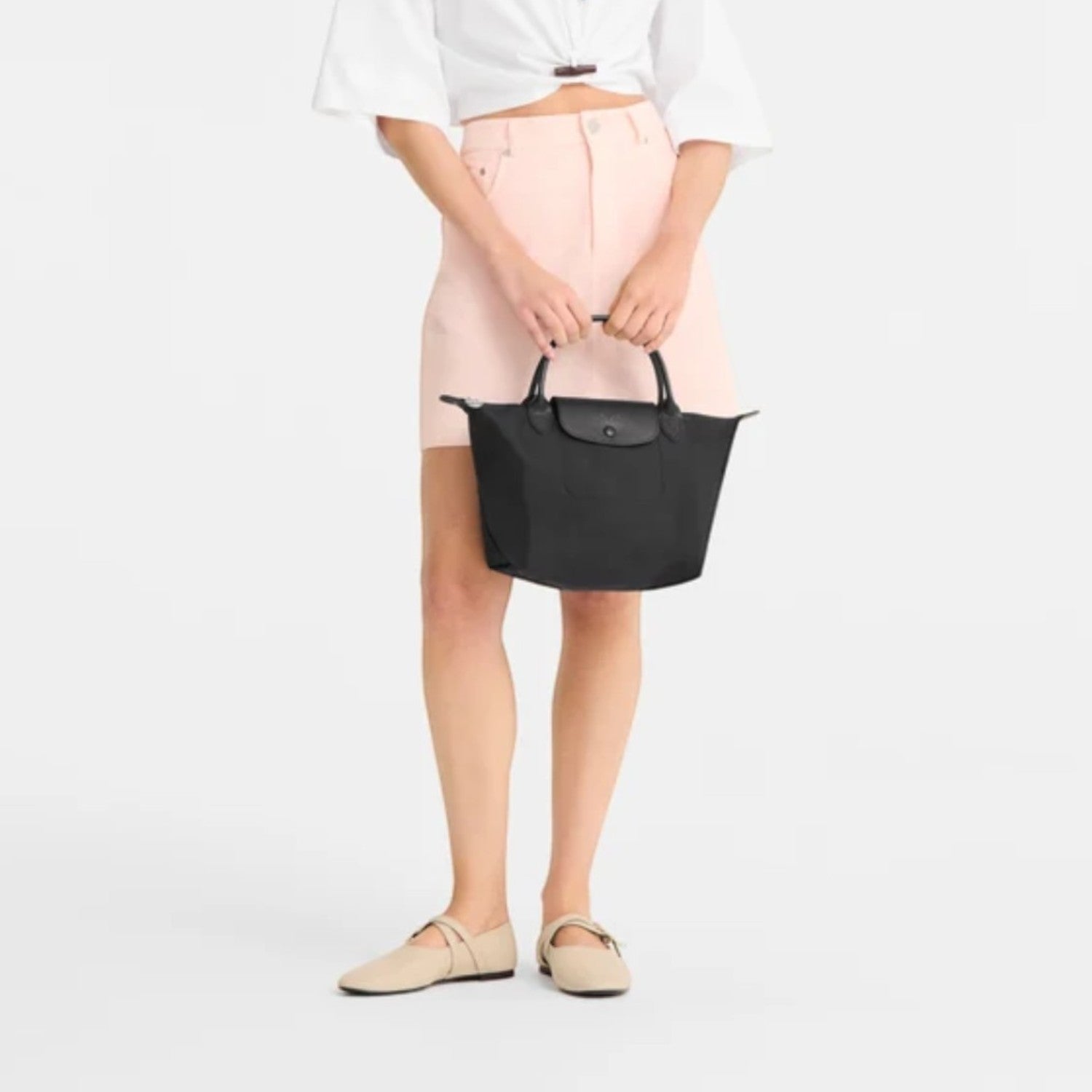 Lieblingstasche Le Pliage One handbag in black nylon with leather trim and handles. Model holds bag.