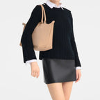 Lieblingstasche Le Pliage One handbag in tan leather, worn by a model in a black sweater and mini skirt.