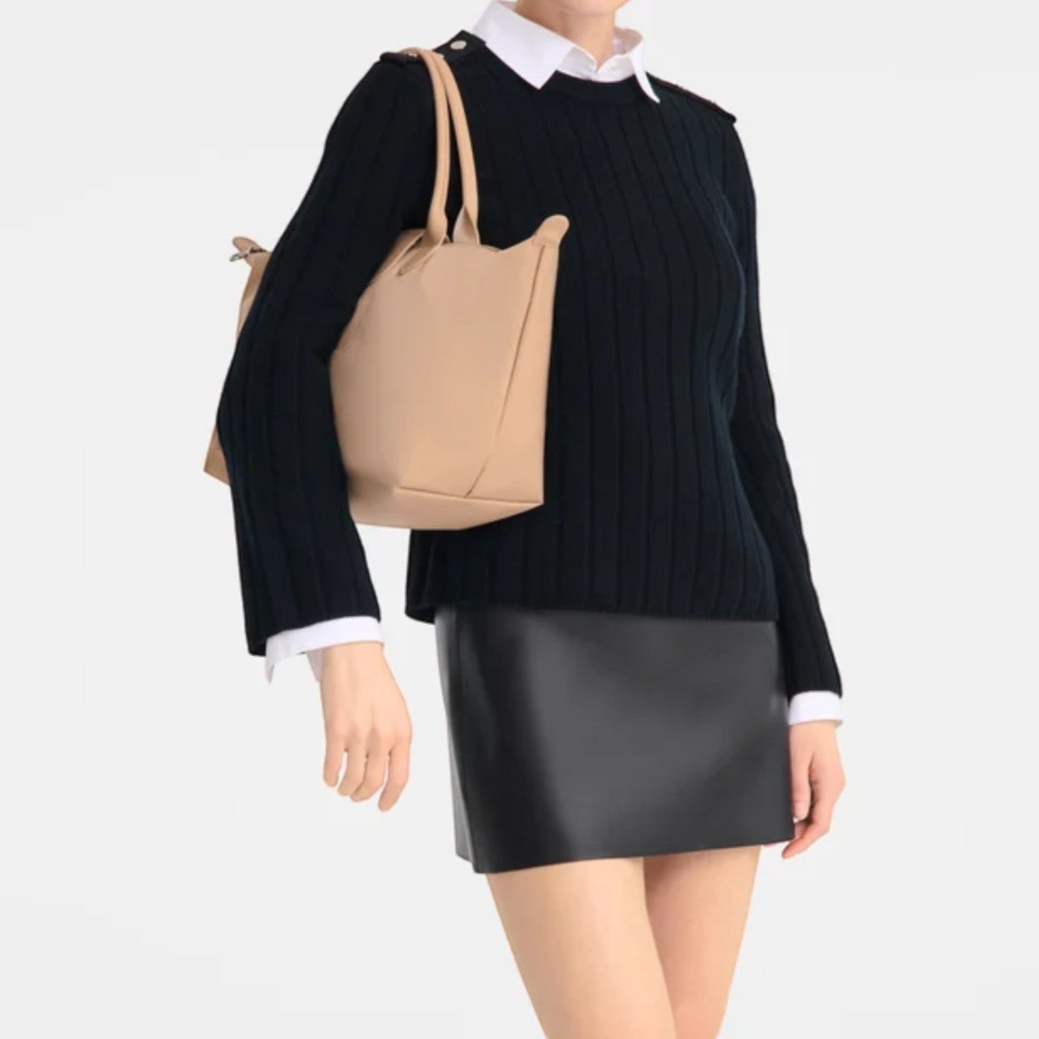 Lieblingstasche Le Pliage One handbag in tan leather, worn by a model in a black sweater and mini skirt.