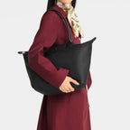 Lieblingstasche Le Pliage One L black nylon tote bag with leather handles and a snap closure, worn by a model.