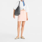 Lieblingstasche Le Pliage One L shoulder bag in dark grey leather with a white knotted top and pink denim skirt.