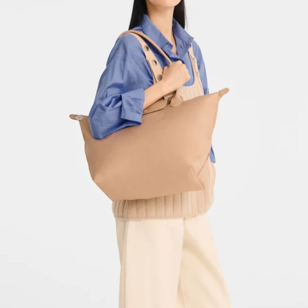 Lieblingstasche Le Pliage One L tote bag in tan nylon with leather trim, worn by a woman.