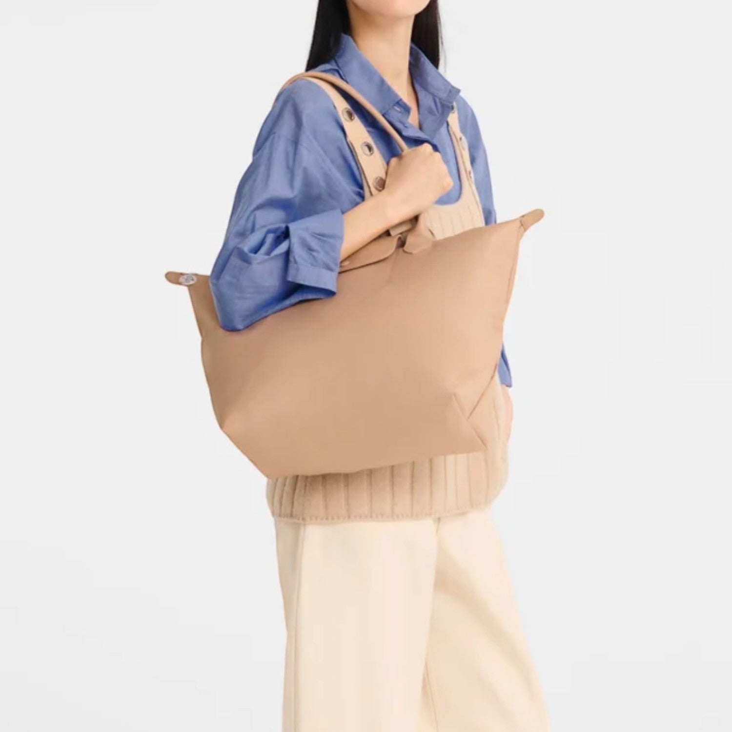 Lieblingstasche Le Pliage One L tote bag in tan nylon with leather trim, worn by a woman.