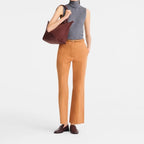 Lieblingstasche Le Pliage One M shoulder bag in burgundy leather, worn by a woman in a grey turtleneck and tan pants.