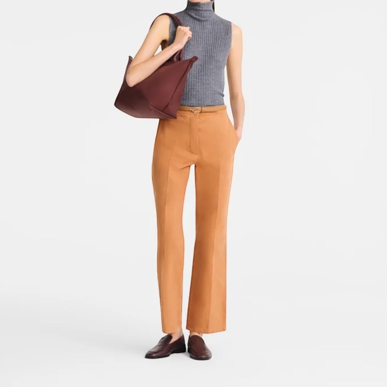 Lieblingstasche Le Pliage One M shoulder bag in burgundy leather, worn by a woman in a grey turtleneck and tan pants.