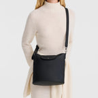 Lieblingstasche Le Pliage Xtra M black leather crossbody bag worn by a blonde model in a cream sweater dress