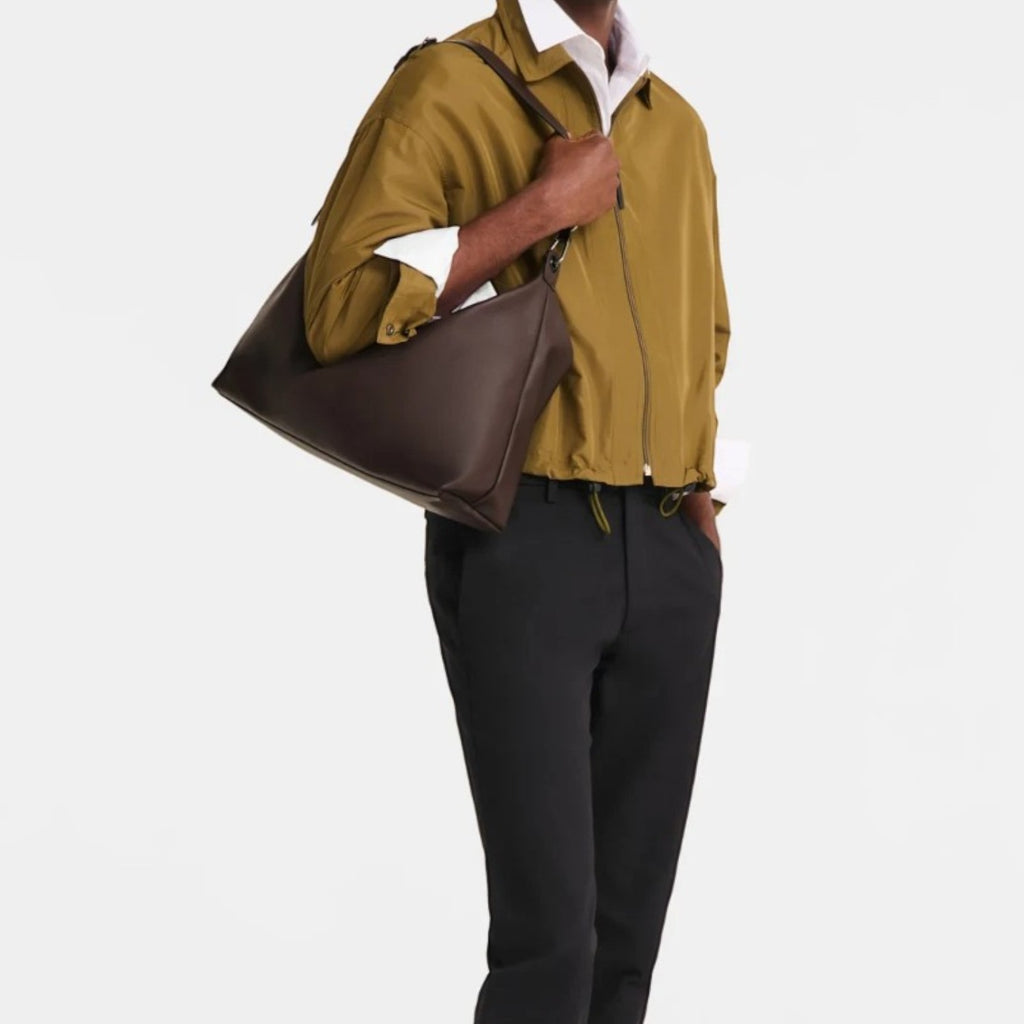 Lieblingstasche Le Pliage Xtra XL shoulder bag in dark brown leather worn by a man in a khaki jacket