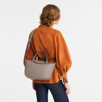 Lieblingstasche Le Pliage Xtra S handbag in taupe smooth leather worn as a shoulder bag by a woman in an orange top
