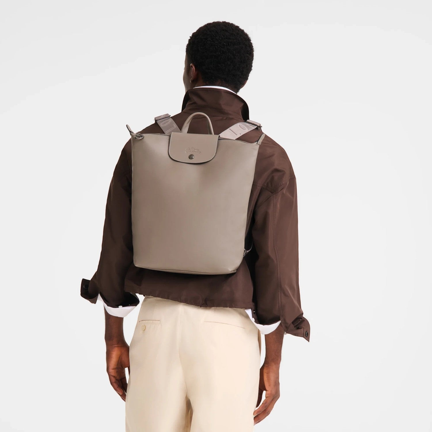 Lieblingstasche Le Pliage Xtra Rucksack M in taupe leather worn on the back by a man in a brown jacket