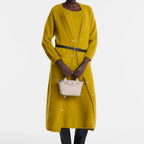 Lieblingstasche Le Pliage Xtra XS handbag in beige leather held by a model wearing a long mustard yellow cardigan