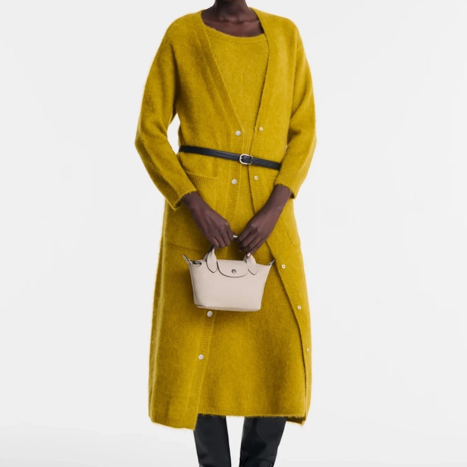 Lieblingstasche Le Pliage Xtra XS handbag in beige leather held by a model wearing a long mustard yellow cardigan