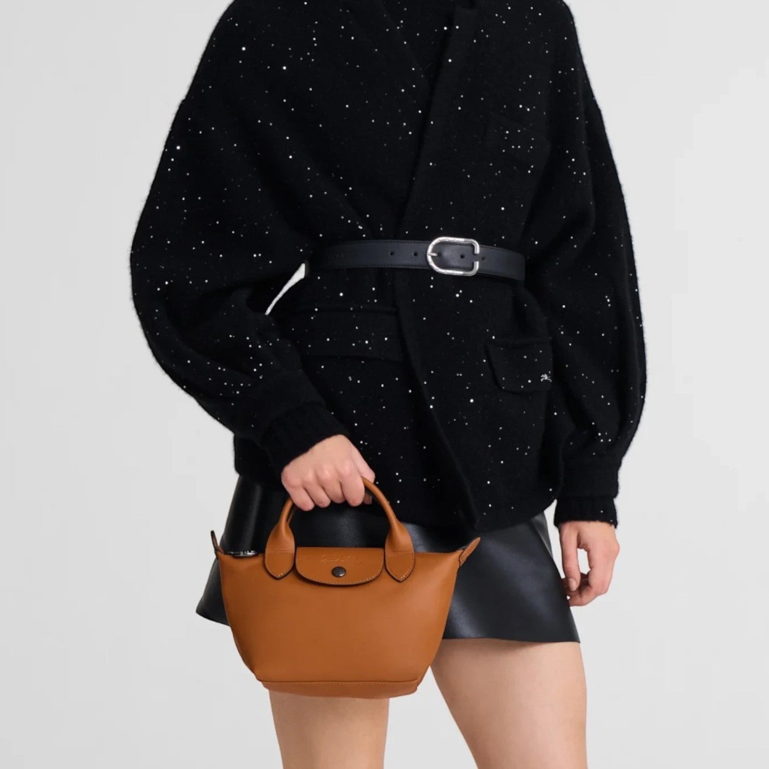 Lieblingstasche Le Pliage Xtra XS handbag in brown smooth cowhide leather held by a model in a black outfit