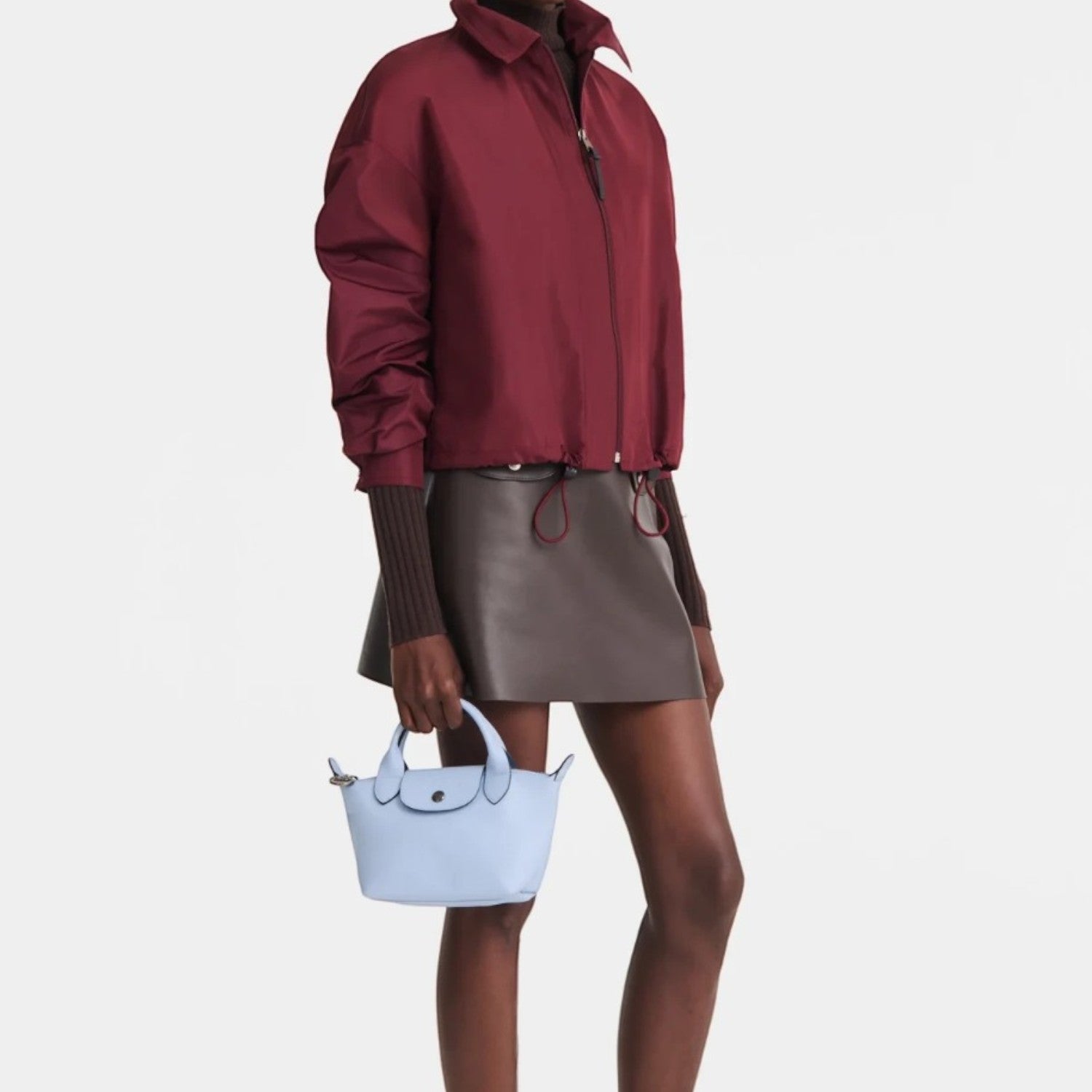 Lieblingstasche Le Pliage Xtra XS handbag in light blue leather held by a model in a burgundy jacket and skirt