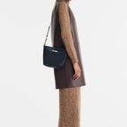 Lieblingstasche Le Roseau XS bucket bag in navy blue leather worn as a crossbody by a model in a brown outfit