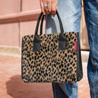Lieblingstasche Daily Shopper XS in leopard print faux fur with black handles held by a person in blue jeans