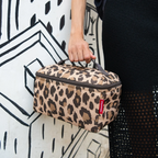 Lieblingstasche leopard print beauty case with top handle held by a person against a black and white mural background