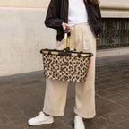 Lieblingstasche Carrybag with leopard print pattern, featuring a sturdy aluminium handle, held by a woman outdoors.