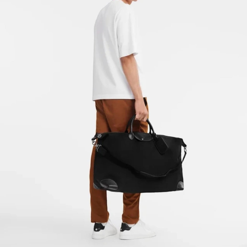Lieblingstasche Longchamp Boxford XL travel bag in black canvas with leather trim held by a man in casual attire