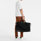Lieblingstasche Longchamp Boxford XL travel bag in black canvas with leather trim held by a man in casual attire