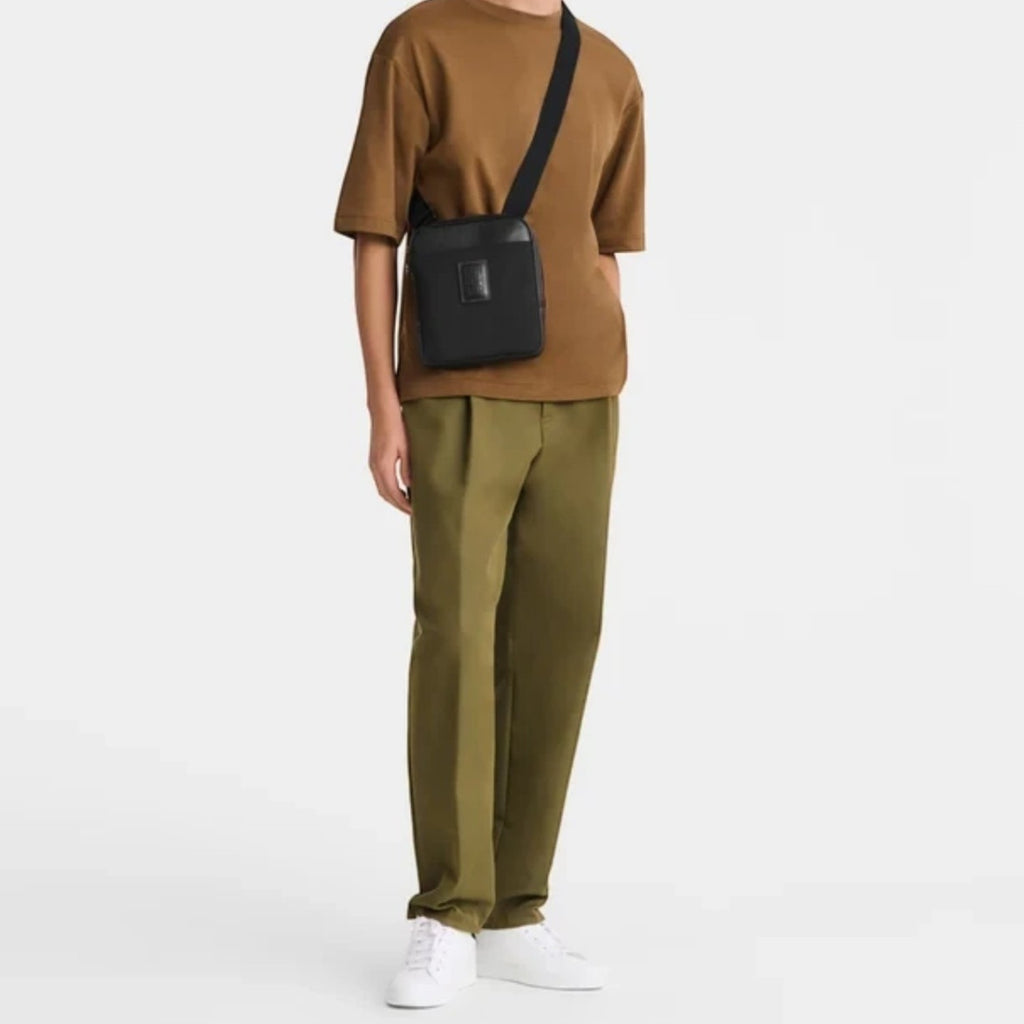 Man wearing a black Longchamp Boxford XS crossbody bag from Lieblingstasche with a brown t-shirt and olive trousers.