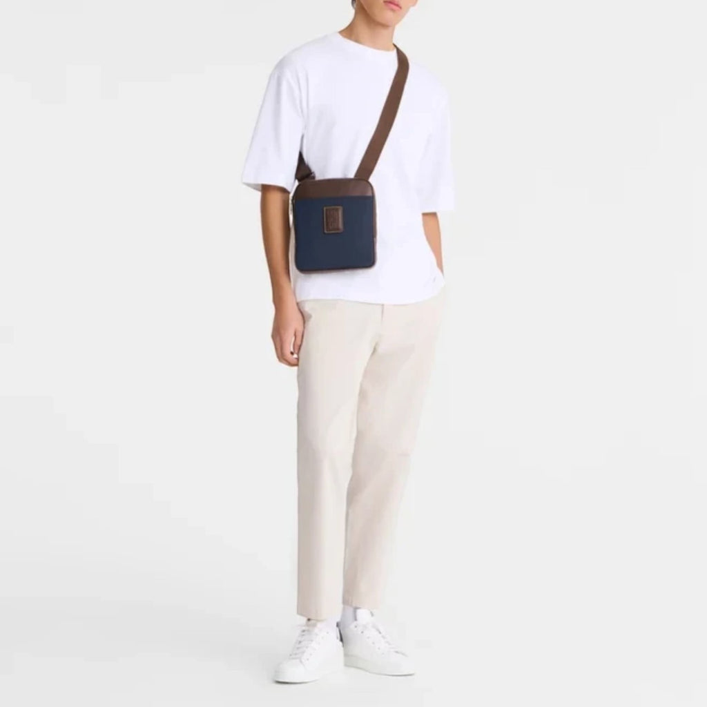 Man wearing a navy and brown Longchamp Boxford XS crossbody bag from Lieblingstasche with a white t-shirt