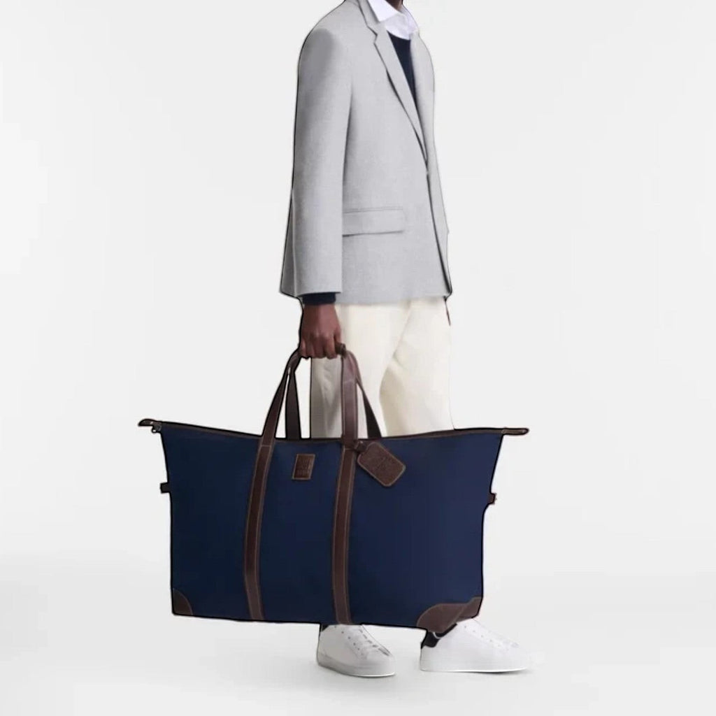 Lieblingstasche Longchamp Boxford navy blue canvas travel bag with brown leather trim held by a man in a grey blazer