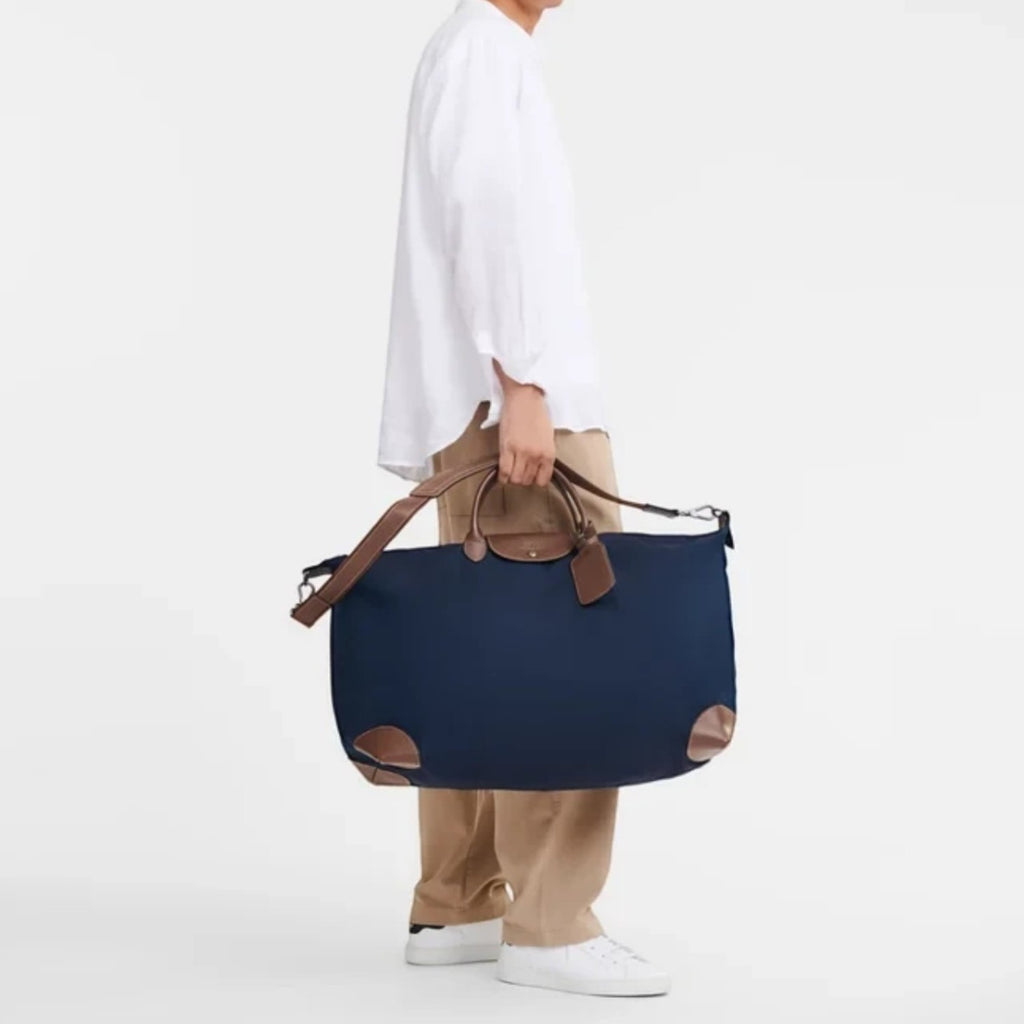 Lieblingstasche Longchamp Boxford XL travel bag in navy blue with brown leather trim held by a man in casual attire