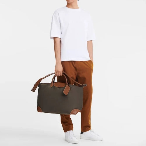 Lieblingstasche Longchamp Boxford travel bag in khaki canvas with brown leather trim held by a man in casual wear