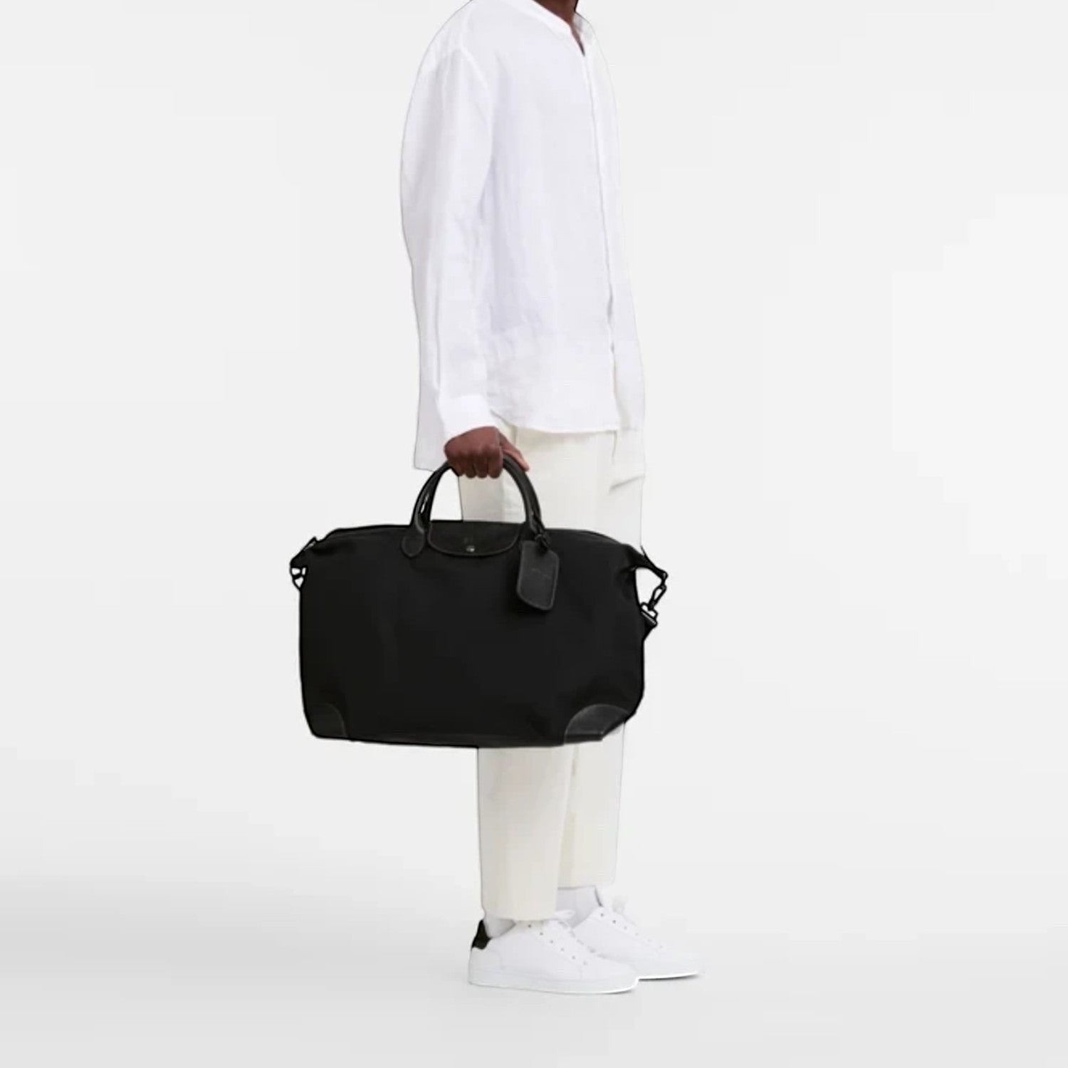 Man holding a black Longchamp Boxford travel bag from Lieblingstasche, featuring a durable design and leather trim.
