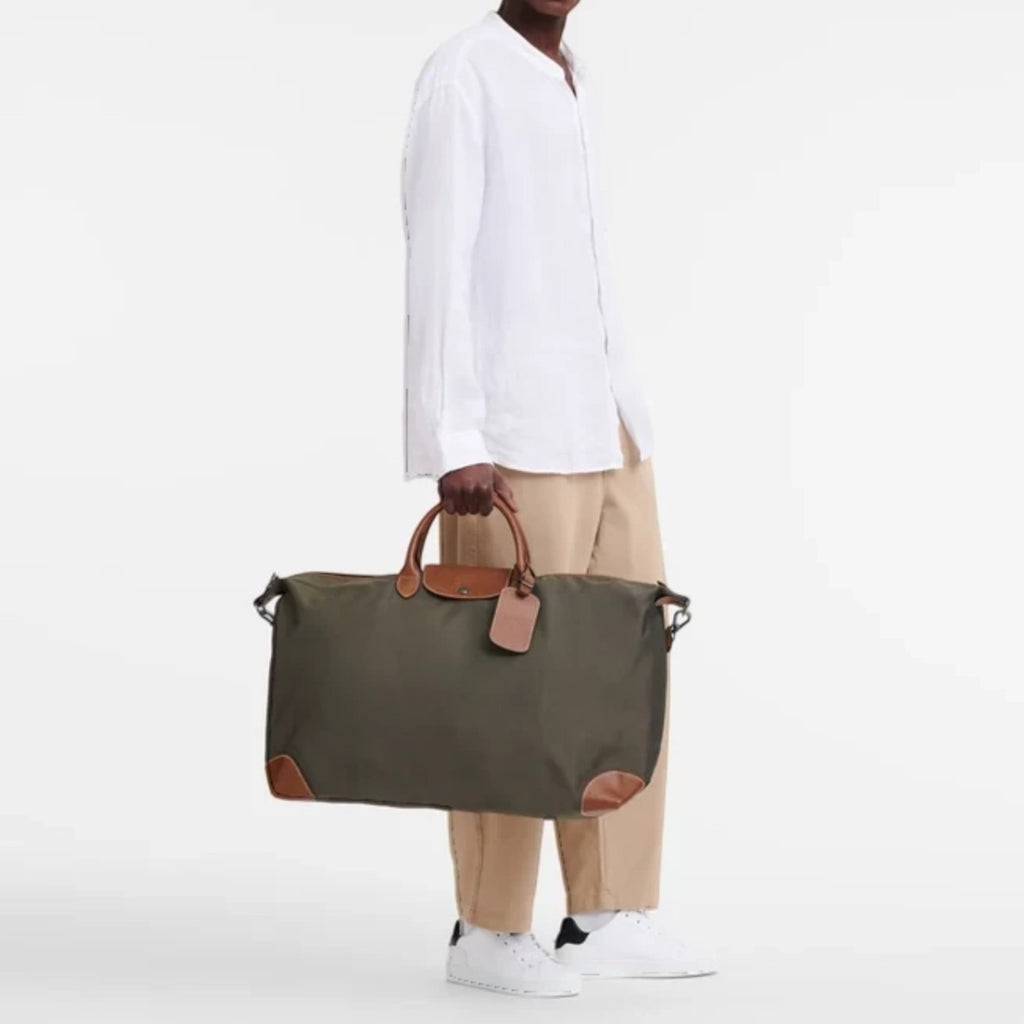 Man holding a green Longchamp Boxford XL travel bag with brown leather trim from Lieblingstasche