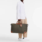 Man holding a green Longchamp Boxford XL travel bag with brown leather trim from Lieblingstasche