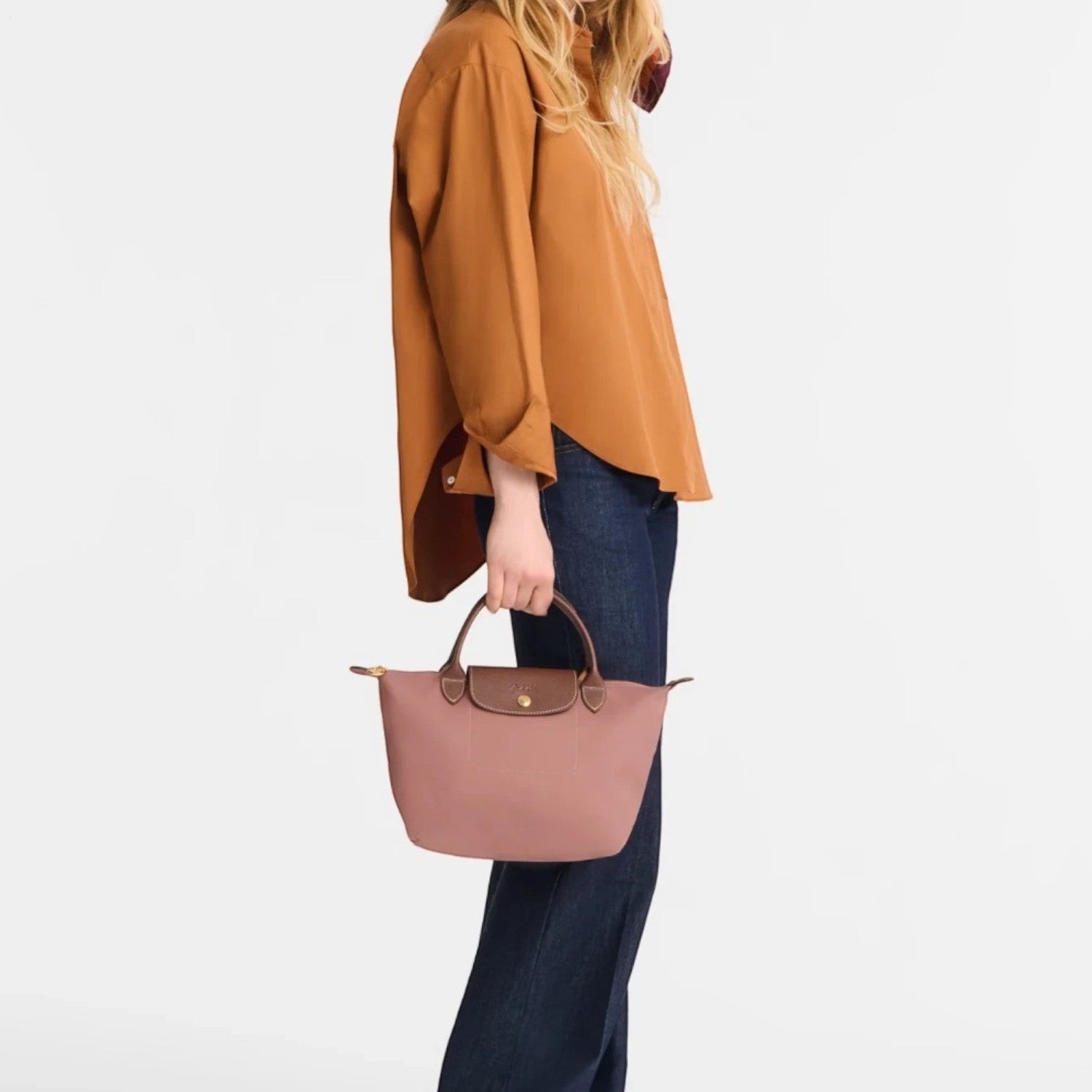 Model holding a dusty pink Longchamp Le Pliage S handbag from Lieblingstasche, featuring brown leather handles.