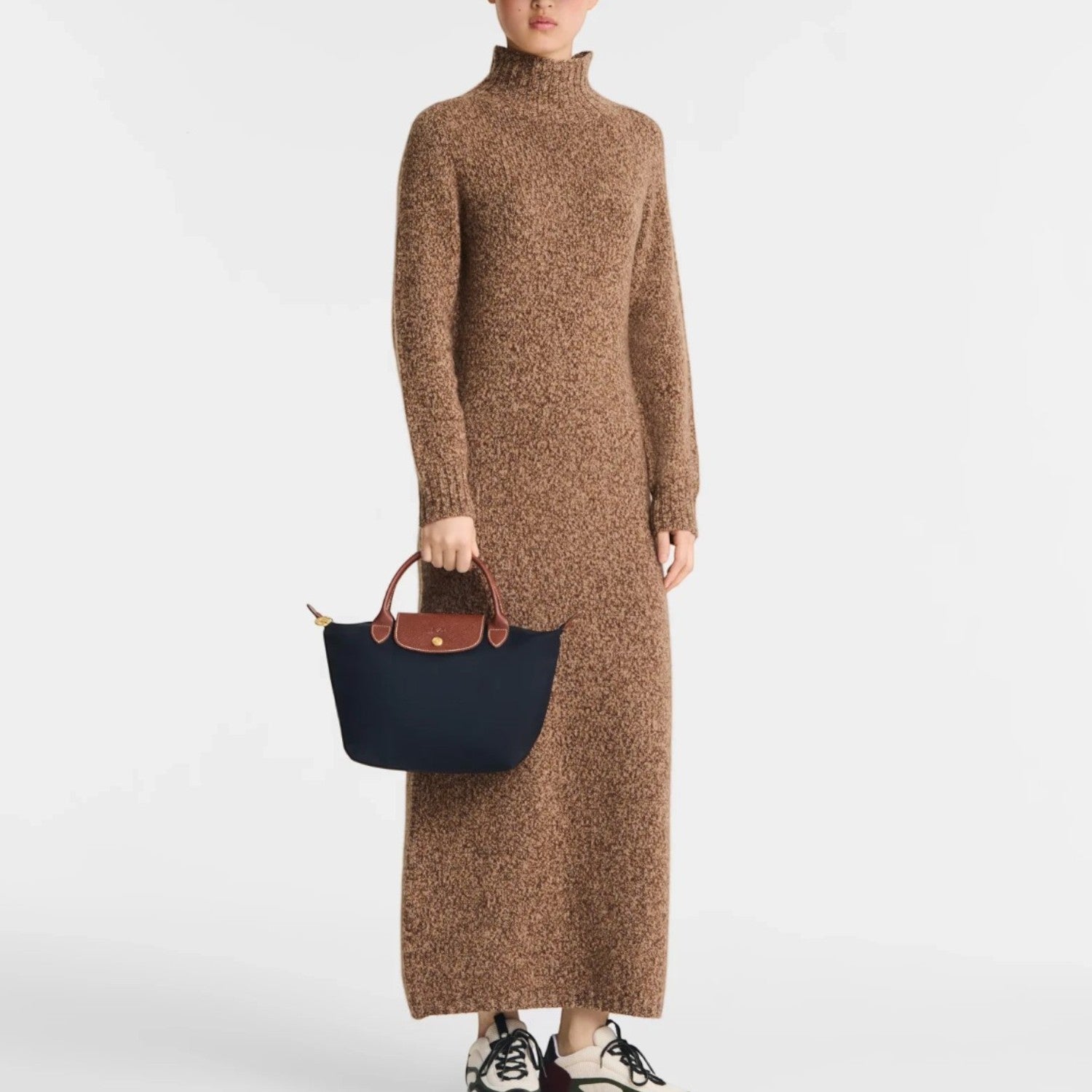 Lieblingstasche Longchamp Le Pliage S handbag in navy blue with brown leather handles held by a model in a brown dress
