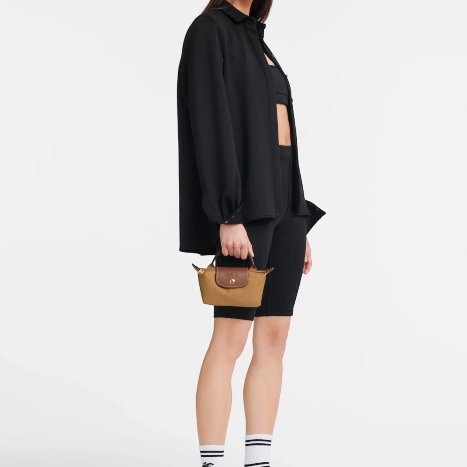 Lieblingstasche Longchamp Le Pliage Pochette in brown held by a model wearing a black outfit against a white background